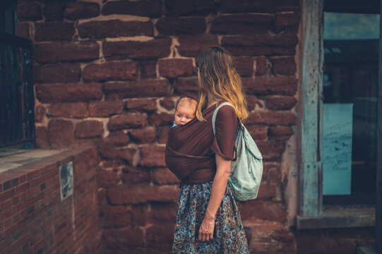 Young mother with her baby in a sling carrier