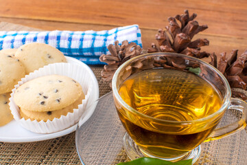 A glass cup of black tea with cookies on a dark greyish marble background.