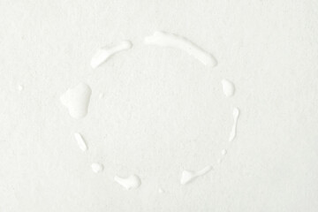 A ring of water droplets on a white wooden table formed by a wet cup after being lifted from the...