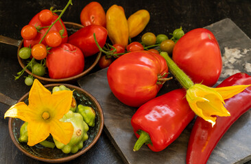 Harvest of autumn farm vegetables. Various types of tomatoes and zucchini on a marble cutting board and on copper pans close-up
