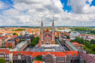 Fototapeta na wymiar Szeged, Hungary - Aerial panoramic view of the Votive Church and Cathedral of Our Lady of Hungary (Szeged Dom) on a sunny summer day with Inner Town Bridge (Belvarosi hid) and blue sky and clouds