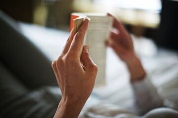hands holding a book, reading in bed