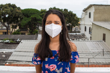 Ni&ntilde;a latina con mascarilla pensando desde su balc&oacute;n