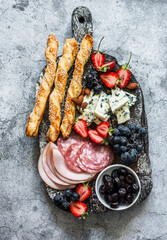 Appetizer board. Gorgonzola, ham, salami, olives, fruit, grassini on a rustic chopping board on a...