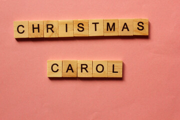 Words Christmas Carol. Wooden blocks with inscription on pink background. The bulletin board. Concept of holiday-Christmas and New year. View from above. Copy space for text. Christmas and New Year.