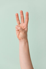 Hand showing letter W on color background. Sign language alphabet