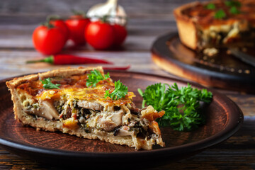 French quiche with chicken and mushrooms on wooden background