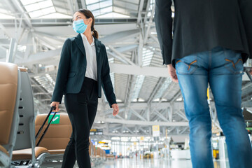 two asian business partners with face mask protection social distancing new normal lifestyle Business travellers walking in airport with luggage motion movement