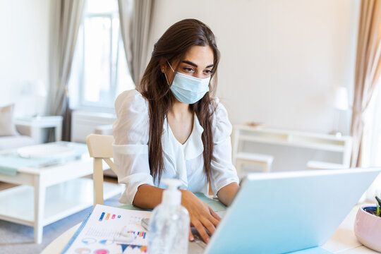 Quarantine, remote job and pandemic concept - woman wearing face protective medical mask for protection from virus disease with laptop computer having video call at home office