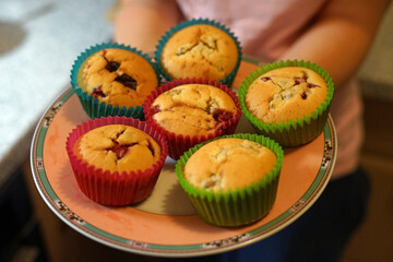 Freshly home made muffins with chocolate in paper cups in woman's hands concept