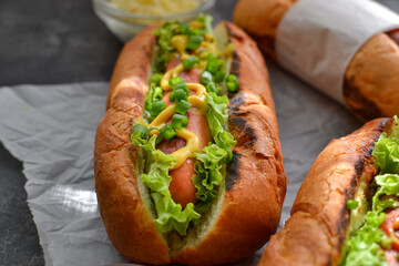 Hot dogs with various fillings. Dark background. food background with copy space. Hot dogs with mustard and ketchup, lettuce, cheese and tomatoes. Close up