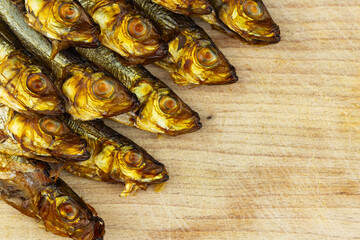 Golden, smoked sprats arranged on wooden cutting board