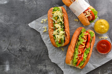 Hot dogs with various fillings. Dark background. food background with copy space. Top view. Hot dogs with mustard and ketchup, lettuce, cheese and tomatoes.