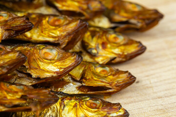 Golden, smoked sprats arranged on wooden cutting board