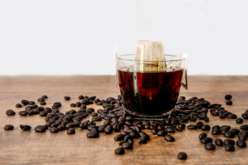 Drip or brewed coffee on wooden texture, paper dropping bag on a cup.