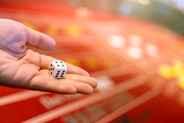 close up Male hand rolling white single dice casino gambling on roulette wheel table casino...