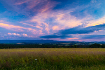 Obraz premium Warm summer sunset over fields and meadows