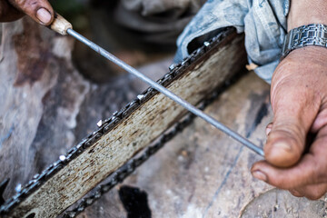 Close up man hands use a rasp to sharpen the blade chainsaw