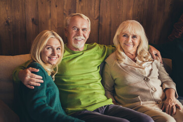 Family meeting thanks giving occasion three elderly people sit sofa hugging wait start dinner living room indoors