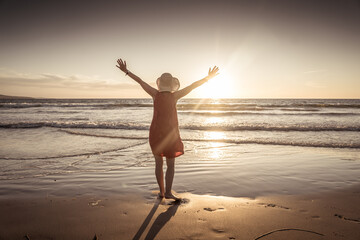 Woman in red with arms outstretched by the sea at sunrise enjoying freedom and life © SB Arts Media