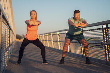Young couple is exercising outdoor on bridge in the city.