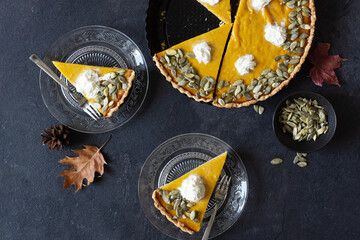 Slices of fresh homemade pumpkin pie on black table top view.
