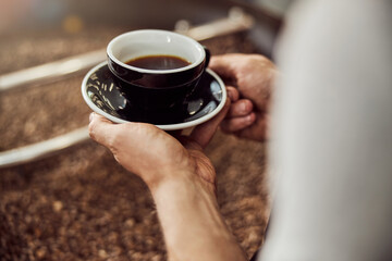 Young man holding cup of coffee and saucer