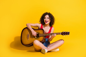 Portrait photo of hipster female musician with curly hair singing song holding keeping playing...