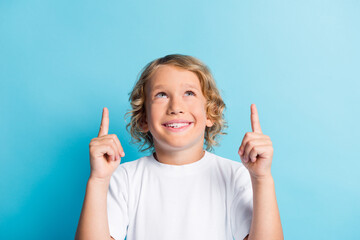 Photo of small boy point index finger empty space look up wear casual style outfit isolated on blue color background