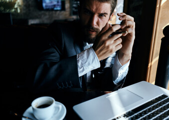 Business man sitting in a cafe in front of a laptop with a cup of coffee work technology lifestyle