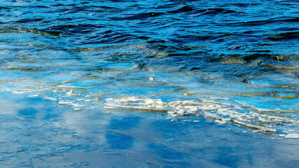 River with dark waves and fragments of ice near the shore