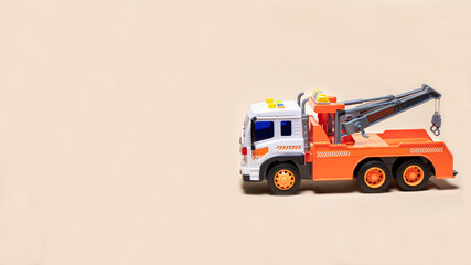 Toy orange tow truck on beige background banner with space for text. Children's car for loading and...