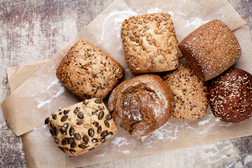 Gold rustic crusty loaves of bread and buns on wooden background. Still life captured from above top view, flat lay.