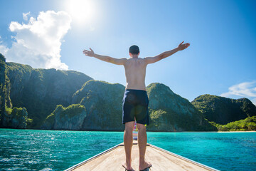 View of man in swimsuit enjoying on thai traditional longtail Boat over beautiful mountain and...