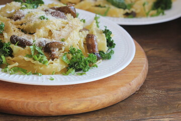 Pasta with creamy sauce, mushrooms and kale, close up