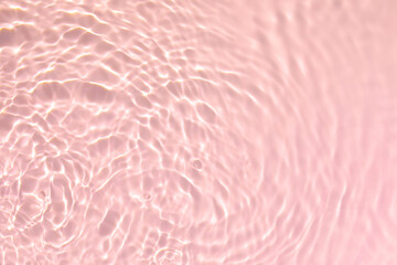 Closeup of pink transparent clear calm water surface texture with splashes and bubbles. Trendy abstract summer nature background. Coral colored waves in sunlight.