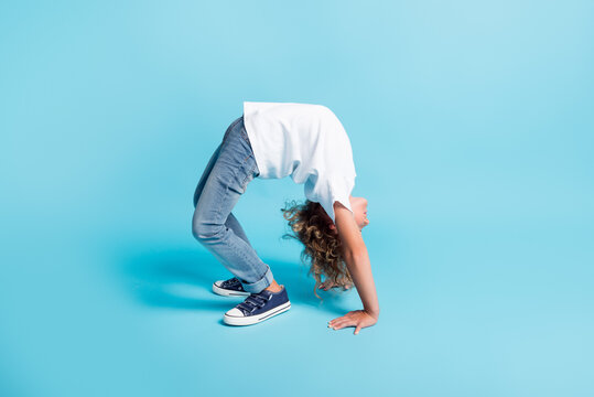 Little kid stand hands bridge yoga pose wear white shirt jeans sneakers isolated blue color background