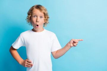 Photo of astonished boy point index finger copyspace wear casual style clothes isolated over blue...