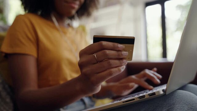 Close-up shot of an african american woman holding a credit card in her hand doing internet banking using laptop