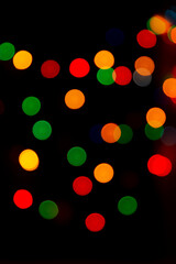 Multicolored bokeh from garlands on a black background. A versatile festive and magical backdrop. 