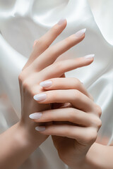 Female hands with white nail design. White nail polish manicured hands. Woman hands on white fabric...