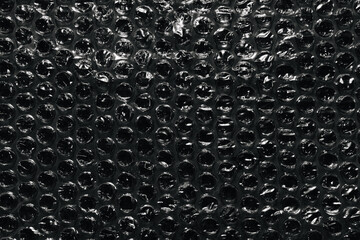 Bubble wrap texture on black background. Packaging with air bubbles.