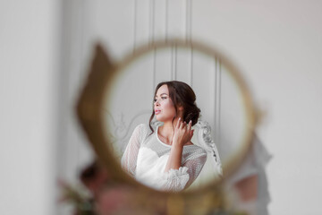 Portrait of the bride in a white wedding dress in a beautiful round mirror