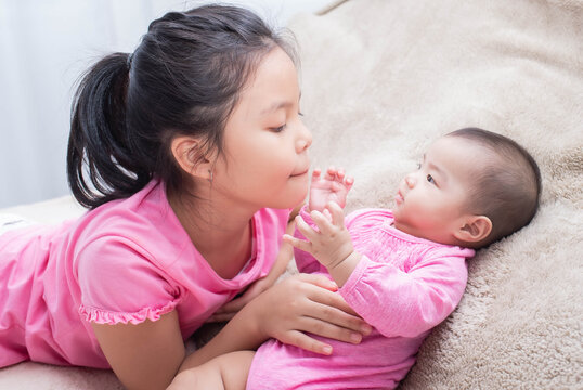 family with children at home. love, trust and tenderness..little sister hugging her newborn brother. toddler kid meeting new sibling. cute girl and new born baby boy relax in a white bedroom.