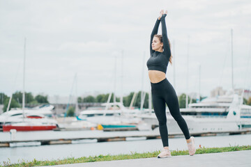 stretching on top of the exercises aerobics a healthy lifestyle. stylish tight comfortable clothing. portrait of a beautiful athletic brunette woman of Caucasian appearance.