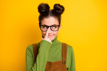 Closeup photo of attractive lady two funny buns clever eyes fix eyeglasses finger geek nerd a-student look shy side wear specs green pullover brown overall isolated yellow color background