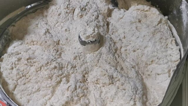 Close up for bread making process by using flour mixing machine in the factory. Stock footage. Preparation of dough with professional kneader machine at the manufacturing.