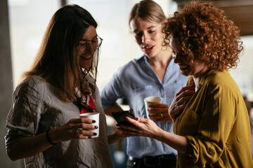 Girlfriends talking and laughing in office. Beautiful women drinking coffee in the office...