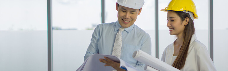 The project owner and the assistant woman wear protective hats. Check the plan with the construction project