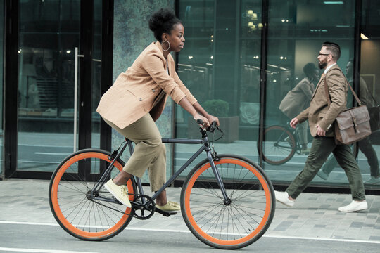 African young woman riding on a bike to her work along the streets in the city